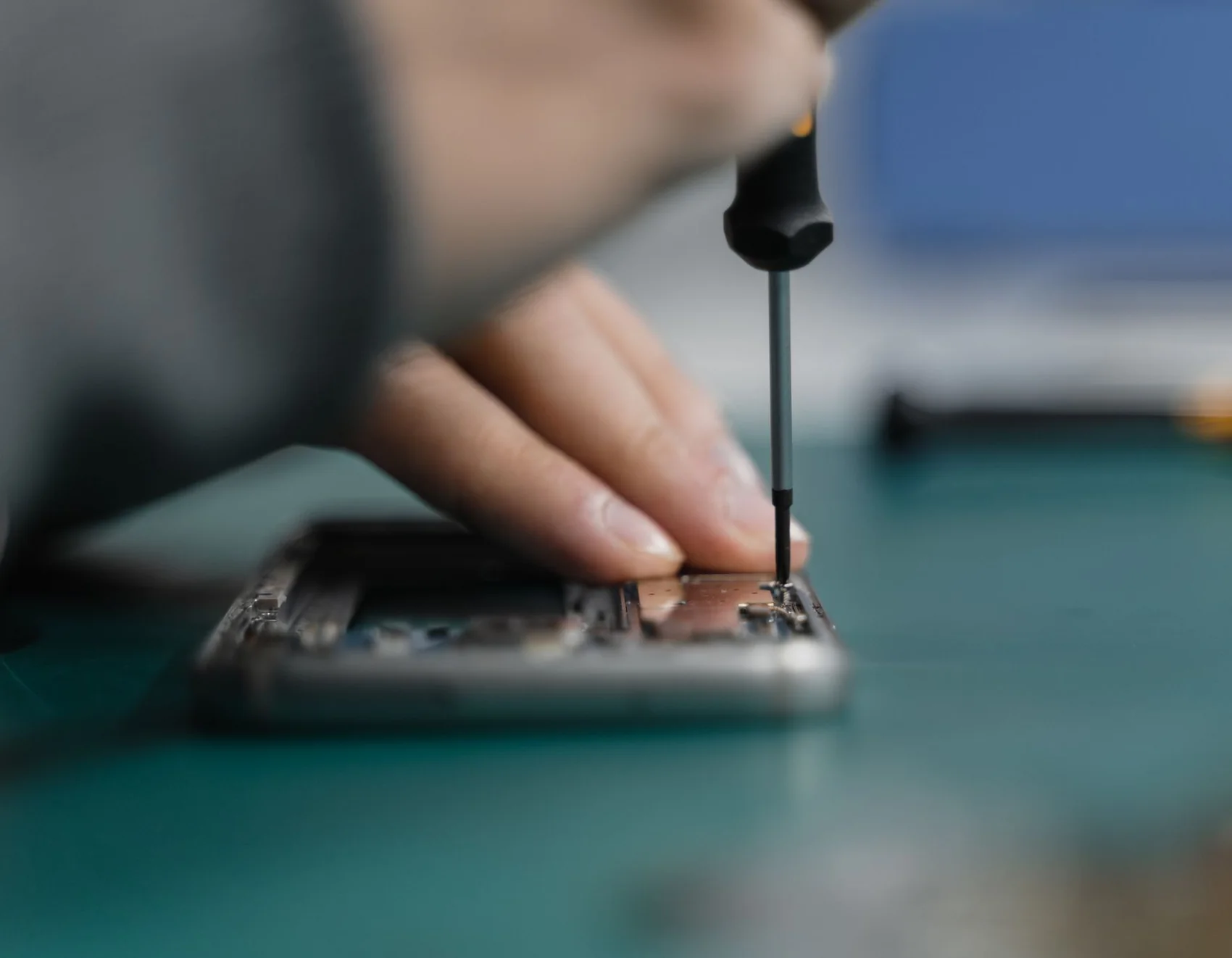 Close-up of hands using a screwdriver to repair an opened phone