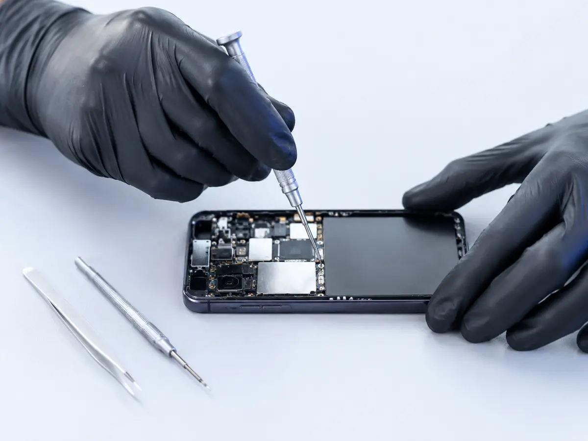 Technician repairing an opened smartphone with precision tools